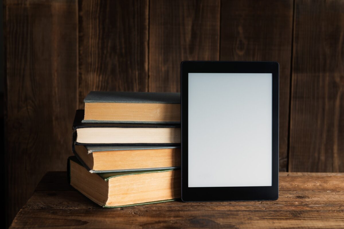 Ebook, digital tablet device, with old real books nearby