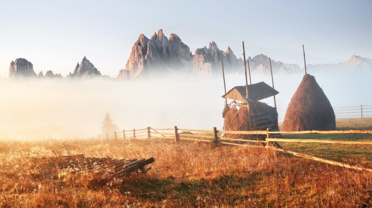 Amazing mountain landscape with fog and a haystack in autumn