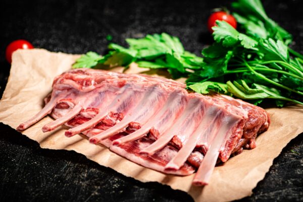 Raw rack of lamb with parsley and tomatoes.