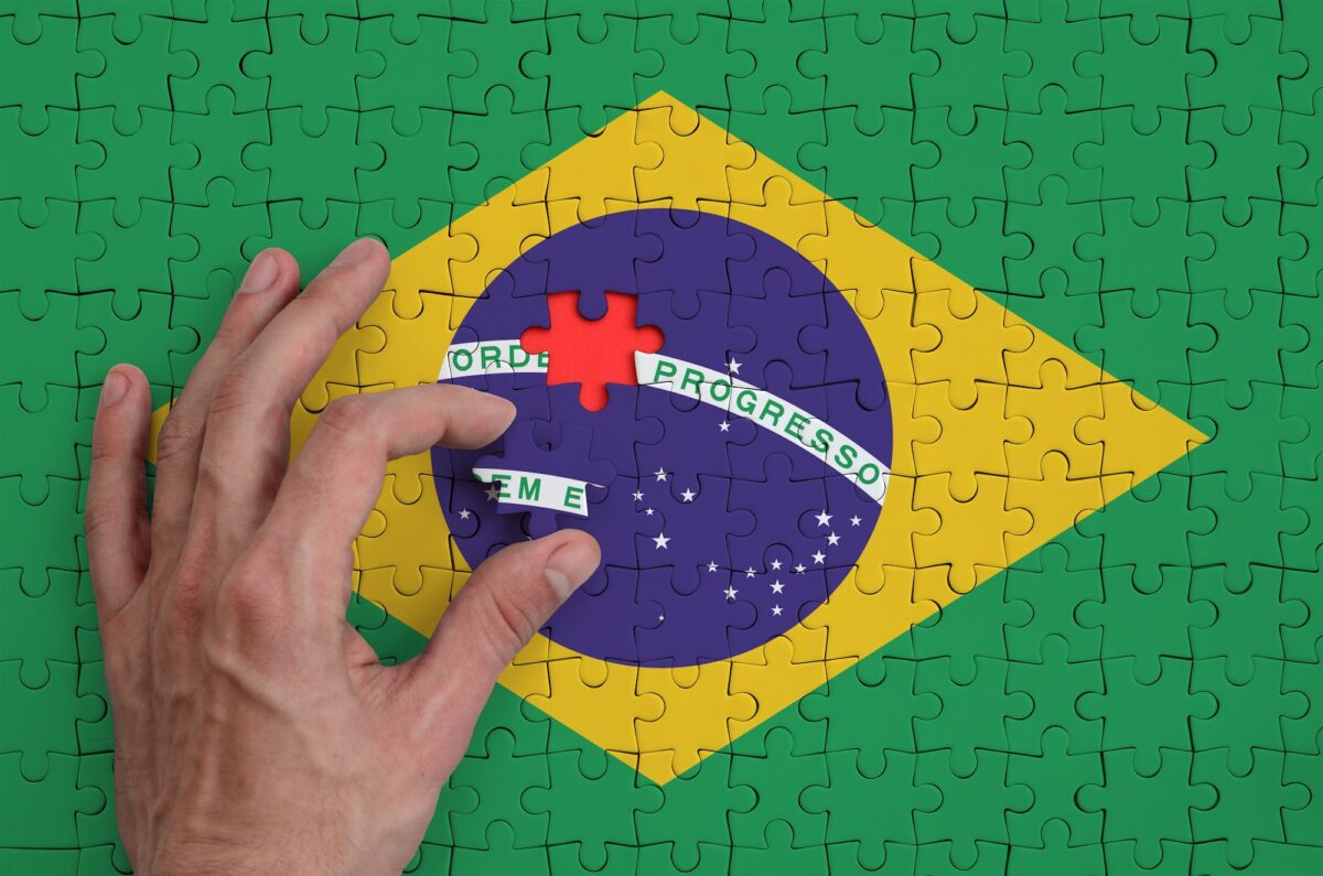 Brazil flag is depicted on a puzzle, which the man's hand completes to fold.