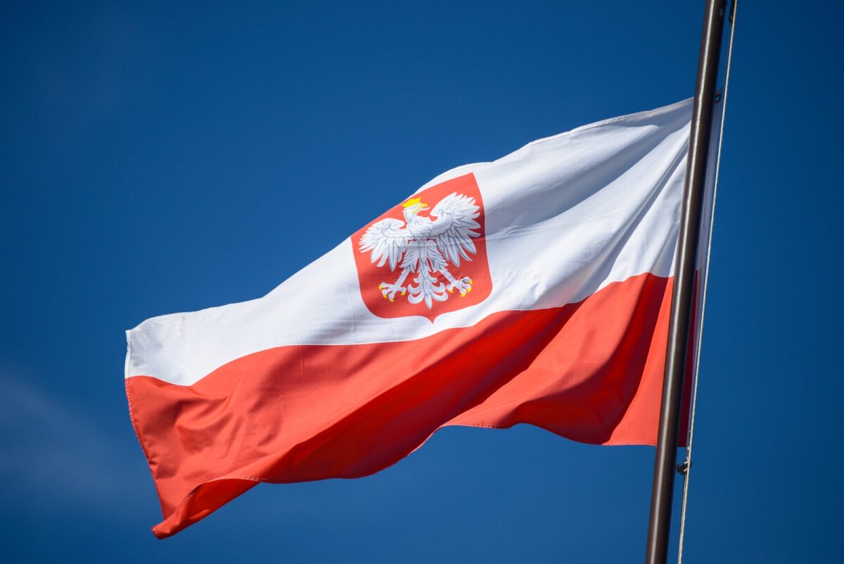 The state flag of Poland with the emblem of the Republic of Poland, on a background of blue sky, in