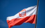 The state flag of Poland with the emblem of the Republic of Poland, on a background of blue sky, in