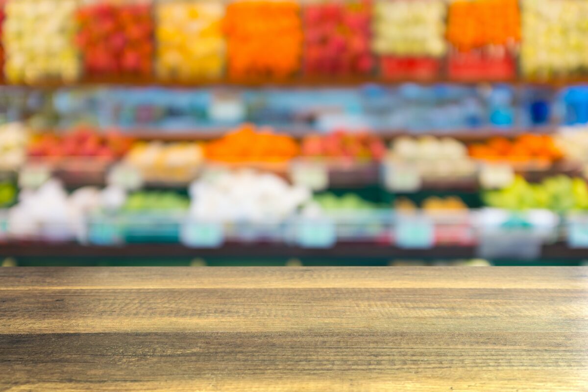 Empty wooden table with blurred fruit shelf in supermarket