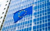 Image of EU flag fluttering on wind against high business office building made of concerete and