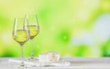 White wine served with cheese plate on light green background.
